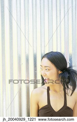 Young woman standing against a corrugated metal wall looking at the side View Large Photo Image Stock Image - Young woman standing against a corrugated metal wall looking at the side. Fotosearch