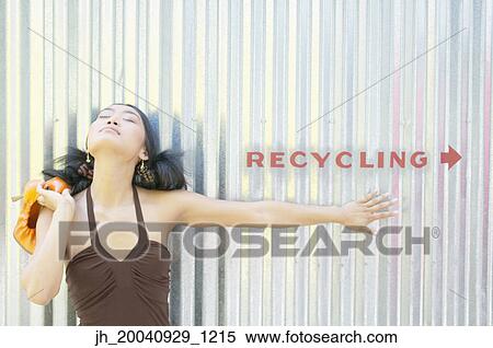 Young woman standing against a corrugated metal wall looking up View Large Photo Image Stock Photography - Young woman standing against a corrugated metal wall looking up. Fotosearch
