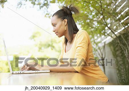Young woman working on a laptop smiling View Large Photo Image Stock Photo - Young woman working on a laptop smiling. Fotosearch