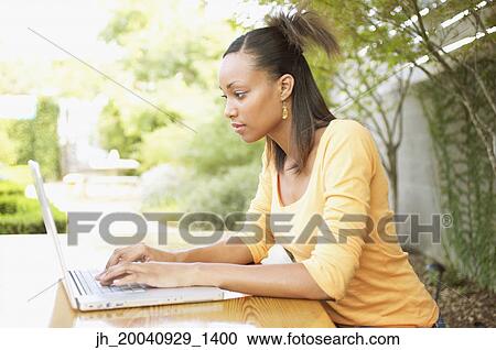 Stock Image - Young woman working on a laptop. Fotosearch