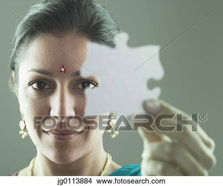 Picture - Close-up of a mid adult woman holding a jigsaw piece. Fotosearch