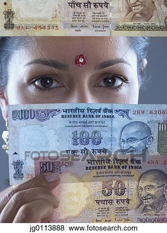 Close-up of a mid adult woman holding a paper currency in front of her face View Large Photo Image Stock Photo - Close-up of a mid adult woman holding a paper currency in front of her face. Fotosearch