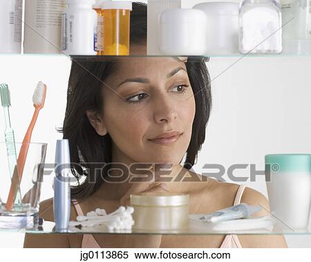 Stock Photography - Close-up of a mid adult woman standing in front of a bathroom cabinet. Fotosearch