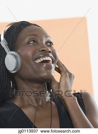Stock Photo - Close-up of a mid adult woman wearing headphones and listening to music. Fotosearch