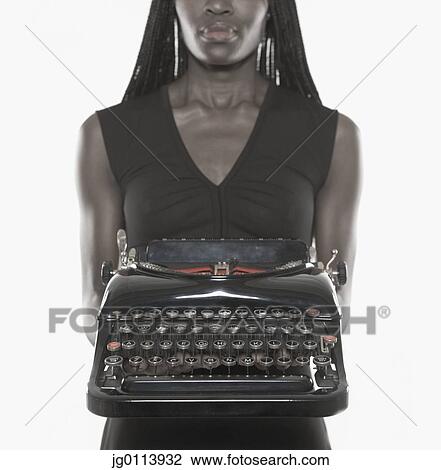 Stock Image - Mid adult woman holding a typewriter. Fotosearch