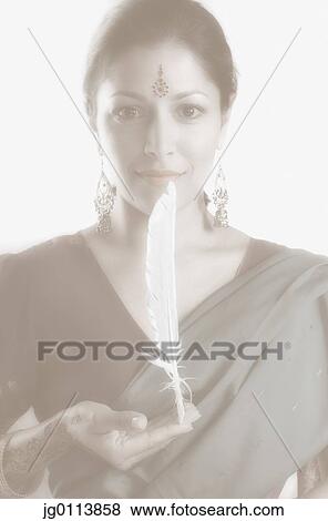 Stock Photo - Portrait of a mid adult woman balancing a feather on her hand. Fotosearch