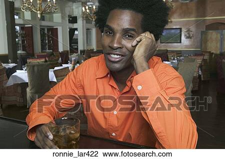 Portrait of a young man sitting at a bar counter holding a glass of whisky View Large Photo Image Stock Image - Portrait of a young man sitting at a bar counter holding a glass of whisky. Fotosearch