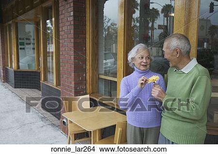 Picture - Senior man giving flower to a senior woman. Fotosearch