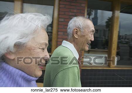Stock Photography - Side profile of a senior couple walking together and smiling. Fotosearch