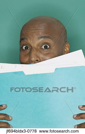 Stock Photo - Businessman hiding behind a blue folder. Fotosearch