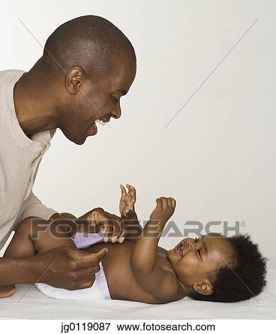 Stock Photo - Father changing his baby daughter's diaper. Fotosearch