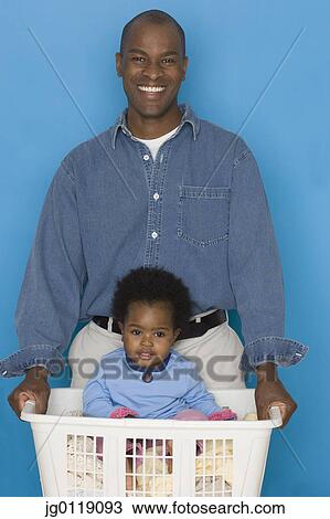 Father doing laundry with baby daughter in hamper View Large Photo Image Stock Image - Father doing laundry with baby daughter in hamper. Fotosearch