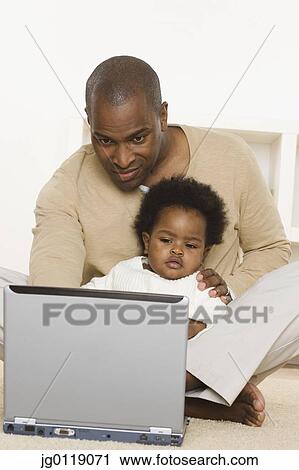 Father using laptop and holding baby daughter View Large Photo Image Stock Image - Father using laptop and holding baby daughter. Fotosearch