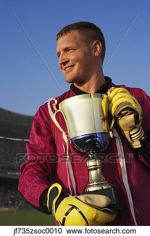 Male goalie triumphantly holding trophy View Large Photo Image Stock Image - Male goalie triumphantly holding trophy. Fotosearch
