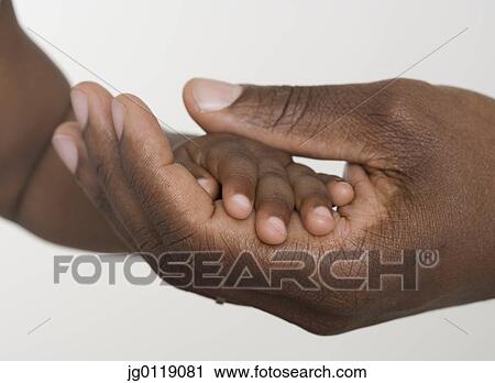 Stock Image - Man holding baby's hand. Fotosearch