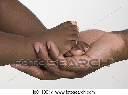 Stock Photo - Man holding baby's tiny feet. Fotosearch
