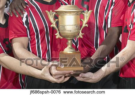 Stock Photograph - Soccer players holding trophy. Fotosearch