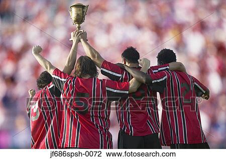 Soccer players triumphantly holding up trophy View Large Photo Image Stock Image - Soccer players triumphantly holding up trophy. Fotosearch