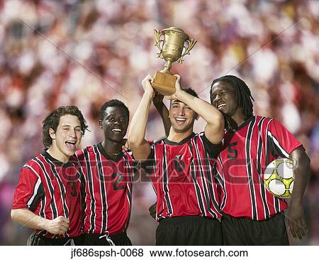 Soccer players triumphantly holding up trophy View Large Photo Image Stock Photo - Soccer players triumphantly holding up trophy. Fotosearch