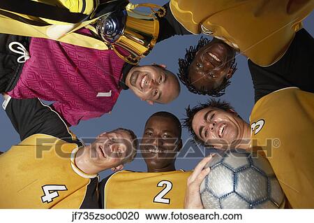 Stock Image - Soccer team posing in a huddle. Fotosearch