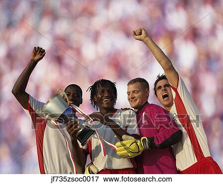 Stock Photo - Soccer team triumphantly holding trophy. Fotosearch