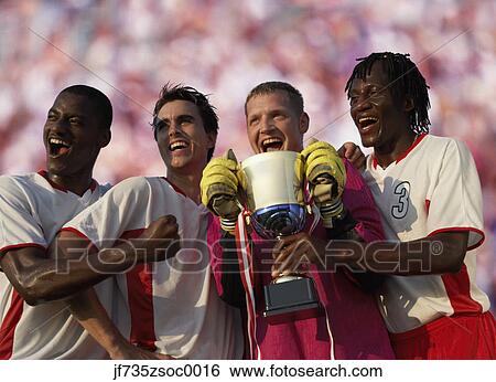 Stock Photograph - Soccer team triumphantly holding trophy. Fotosearch
