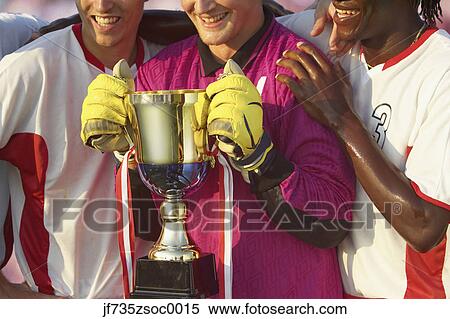 Stock Photography - Soccer team triumphantly holding trophy. Fotosearch