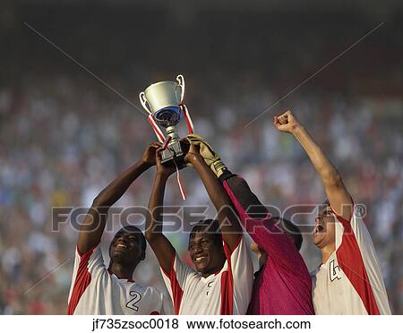 Stock Photo - Soccer team triumphantly holding up trophy. Fotosearch