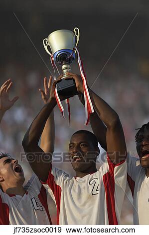 Soccer team triumphantly holding up trophy View Large Photo Image Stock Photo - Soccer team triumphantly holding up trophy. Fotosearch