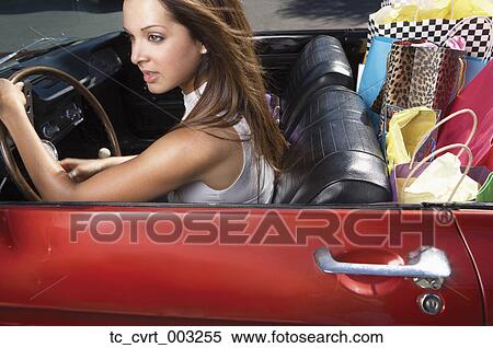 Stock Photography - Woman driving convertible stuffed with shopping bags. Fotosearch