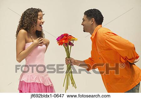 Young man giving girlfriend a bunch of flowers View Large Photo Image Stock Photo - Young man giving girlfriend a bunch of flowers. Fotosearch