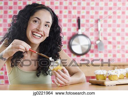 Picture - Young woman frosting cupcakes . Fotosearch