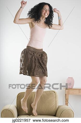 Young woman jumping on the couch View Large Photo Image Stock Photo - Young woman jumping on the couch. Fotosearch