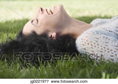 Stock Photo - Young woman laying on grass. Fotosearch