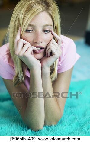 Stock Photo - Young woman leaning on her elbows while thinking. Fotosearch