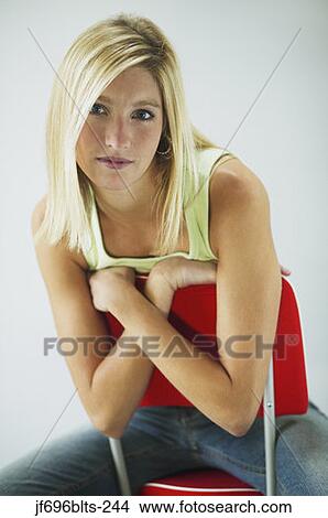Picture - Young woman leaning over the back of a chair. Fotosearch