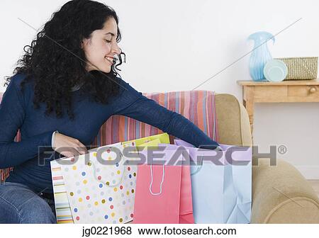 Young woman looking through shopping bags View Large Photo Image Stock Photo - Young woman looking through shopping bags. Fotosearch