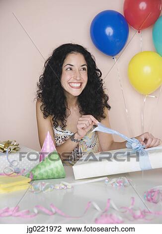 Young woman opening birthday present View Large Photo Image Stock Image - Young woman opening birthday present. Fotosearch
