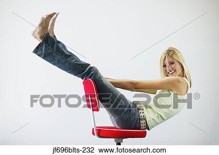Stock Image - Young woman playing in a chair. Fotosearch