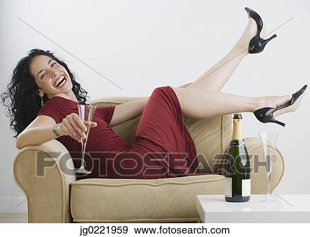 Stock Photo - Young woman relaxing with wine at dinner party. Fotosearch
