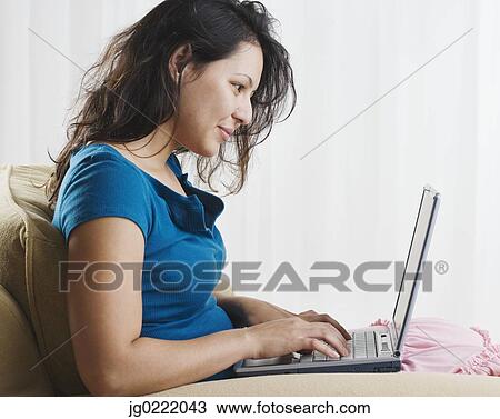 Stock Image - Young woman using laptop. Fotosearch