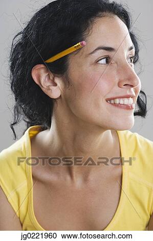 Young woman wearing pencil behind her ear View Large Photo Image Stock Image - Young woman wearing pencil behind her ear. Fotosearch