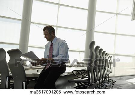 Stock Photography - Businessman reading paperwork in conference room. Fotosearch