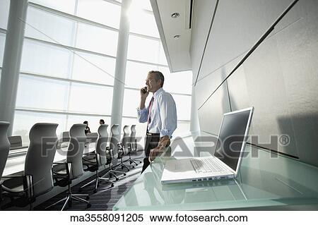 Businessman talking on cell phone in conference room View Large Photo Image Stock Photography - Businessman talking on cell phone in conference room. Fotosearch