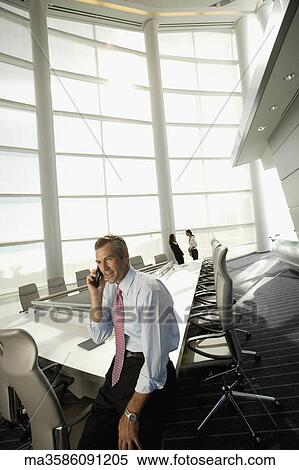 Stock Photography - Businessman talking on cell phone in conference room. Fotosearch
