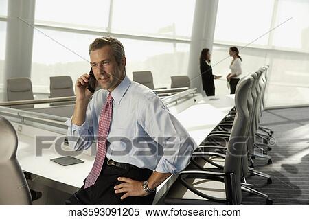 Businessman talking on cell phone in conference room View Large Photo Image Stock Photography - Businessman talking on cell phone in conference room. Fotosearch