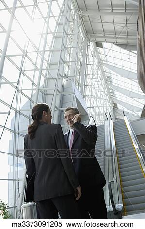 Stock Photography - Businesspeople talking in airport. Fotosearch