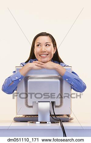 Stock Image - Businesswoman daydreaming while hugging computer. Fotosearch