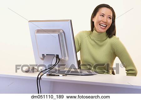 Businesswoman laughing while sitting at computer View Large Photo Image Stock Photo - Businesswoman laughing while sitting at computer. Fotosearch