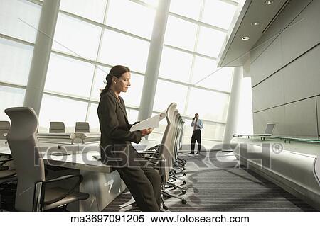 Stock Photography - Businesswoman reading paperwork in conference room. Fotosearch
